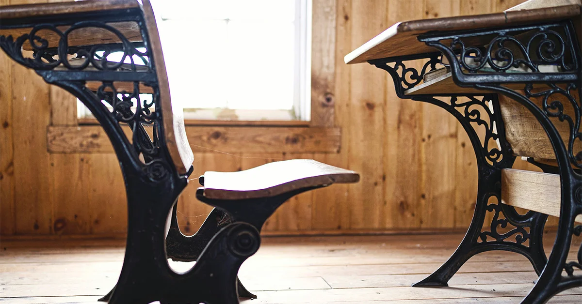 photo of an old wooden and iron desk and bench seat in a one-room school house (featured image: "Education Reform Leaders: Major Figures in Transforming Modern Education" article)